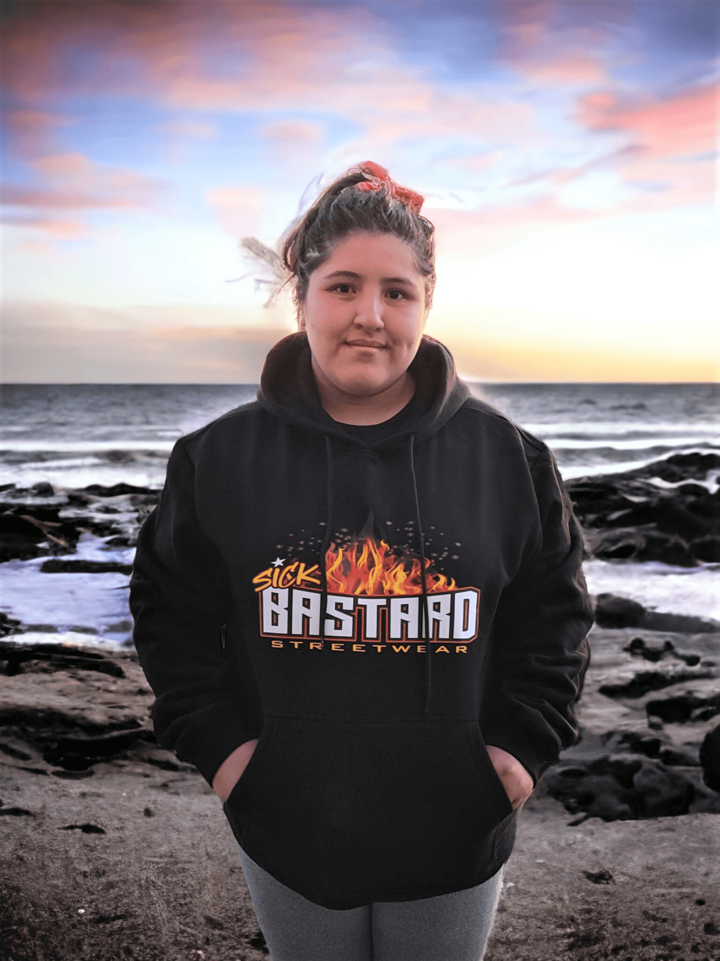Young person wearing the Arrive Raise Hell Leave Hoodie by Sick Bastard Streetwear near the ocean.