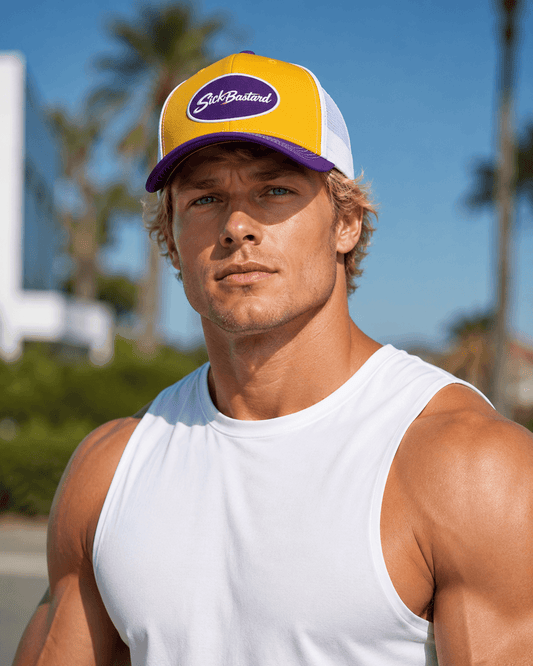 Man wearing a purple and gold snapback hat with a white mesh back, posing outdoors in a casual tank top.