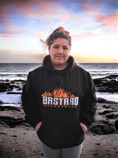 Young person wearing the Arrive Raise Hell Leave Hoodie by Sick Bastard Streetwear near the ocean.