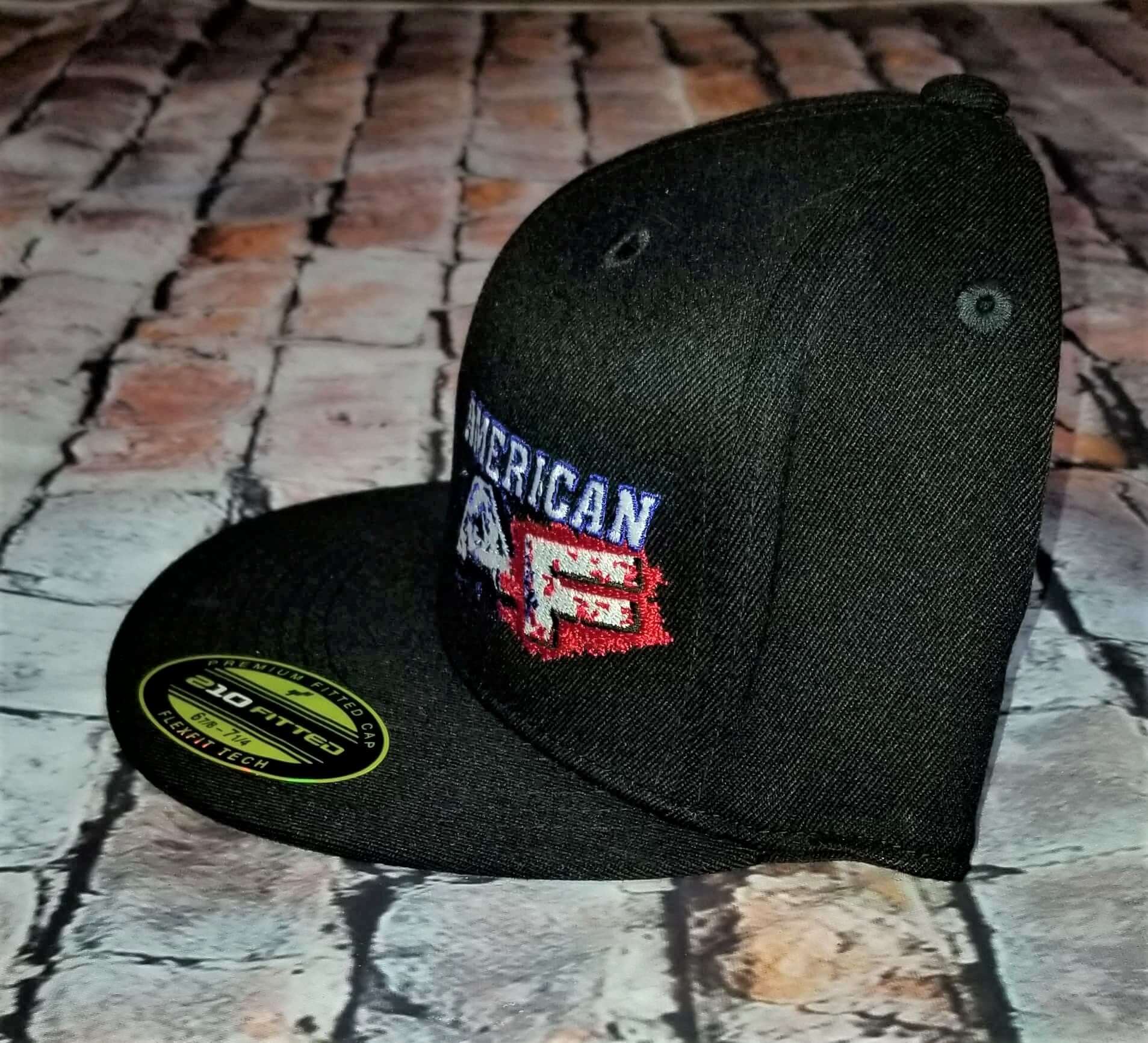 American flag flexfit hat displayed from the side, featuring embroidered text and a flat bill design.