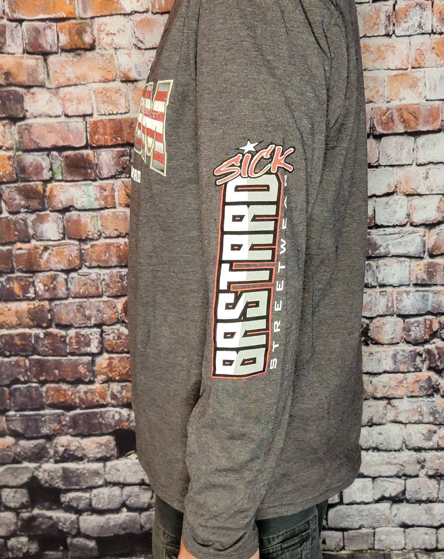 Side view of a person wearing a Freedom Long Sleeve Shirt by Sick Bastard Streetwear against a brick background.