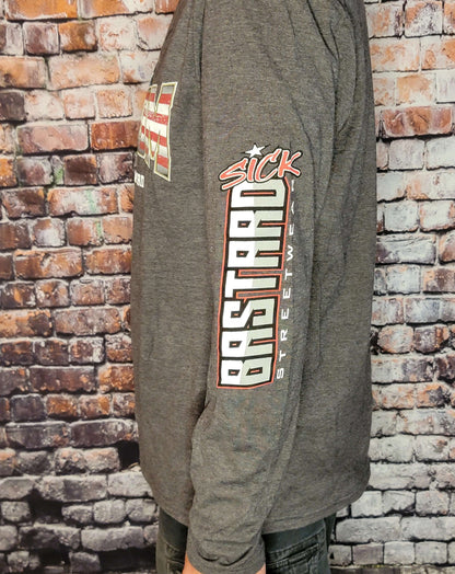 Side view of a person wearing a Freedom Long Sleeve Shirt by Sick Bastard Streetwear against a brick background.