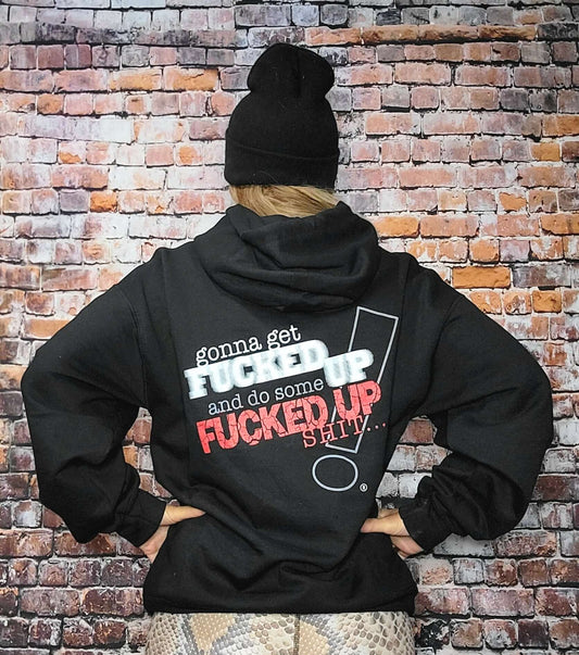 Back view of person wearing a Fucked Up hoodie with bold text on a brick background.