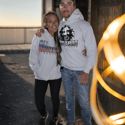 Couple wearing cheap pullover hoodies featuring Sick Bastard logos outdoors.